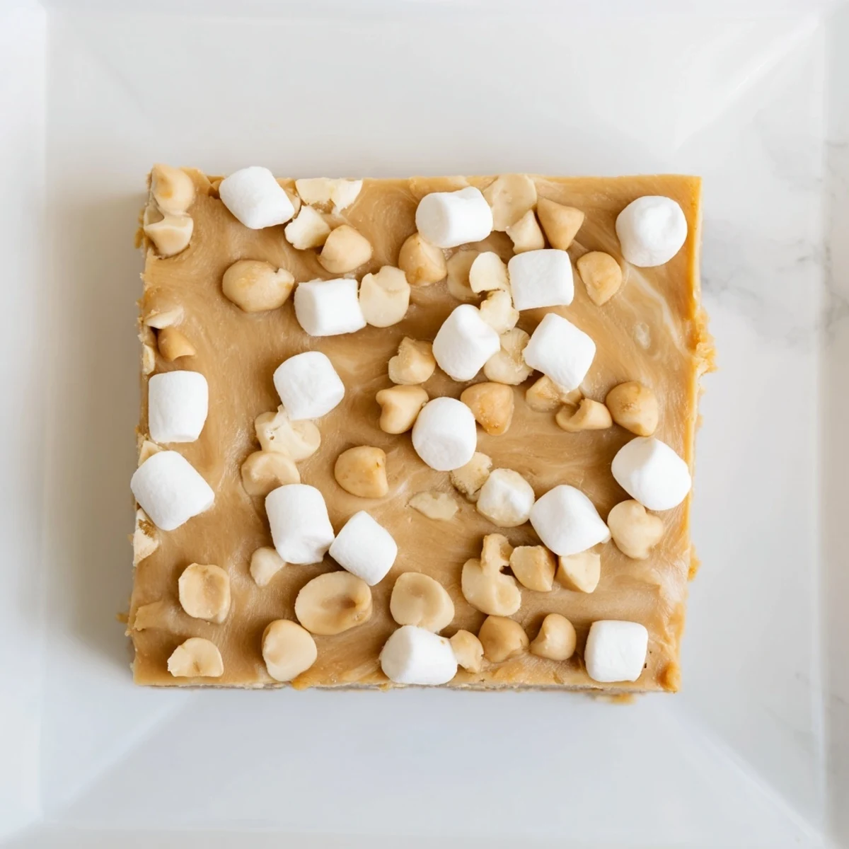 Close-up of decadent 5-Minute Peanut Butter Marshmallow Fudge, swirled with marshmallow fluff, awaiting a bite.