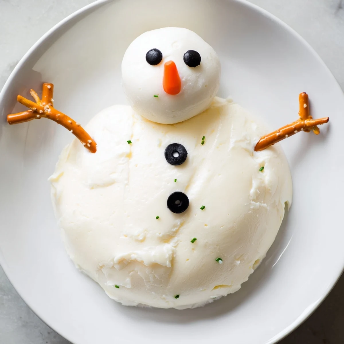Melted Snowman Cheese Bites are festive, creamy appetizers: snowman-shaped cheese balls with olive eyes.