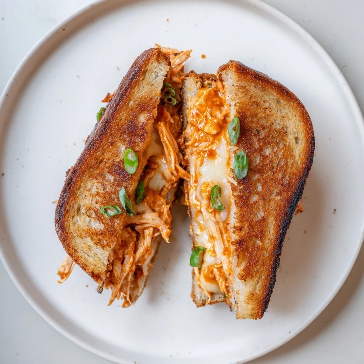 Golden-brown Gochujang Mayo Chicken Sandwich grilled cheese oozes melted cheese, offering spicy, savory satisfaction.