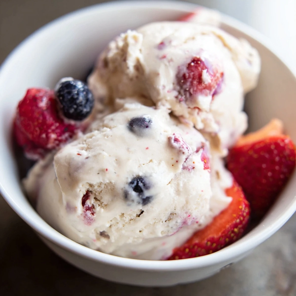 Scoops of homemade Cottage Cheese Ice Cream, looking smooth, are ready to be served in a bowl.