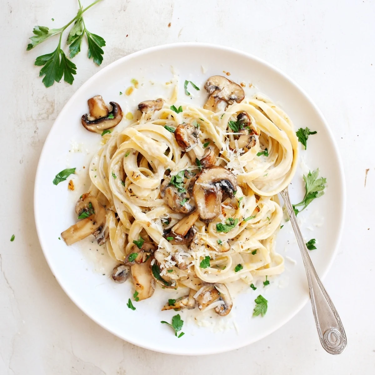 A close-up of Creamy Mushroom Linguine reveals tender mushroom slices and melted Parmesan, garnished with fresh chopped parsley on top.  