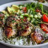 A close-up of a Pesto Chicken Bowl reveals golden chicken, pine nuts, and greens, ready for a nourishing lunch or weeknight dinner.