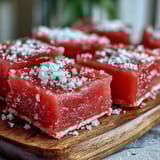 Fragrant guava cheese candy squares arranged on a rustic wooden board with lime wedges.