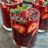 A vibrant glass of Homemade Starbucks Strawberry Açaí Refresher with fresh strawberry slices and açaí swirls.