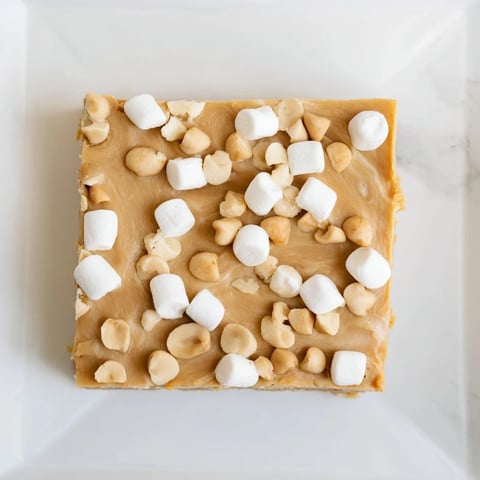 Close-up of decadent 5-Minute Peanut Butter Marshmallow Fudge, swirled with marshmallow fluff, awaiting a bite.