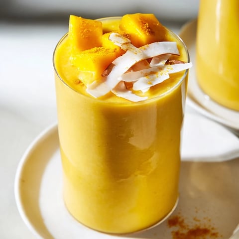 Golden-hued Mango Turmeric Smoothie, blended smooth and vibrant in a tall glass, ready to drink.