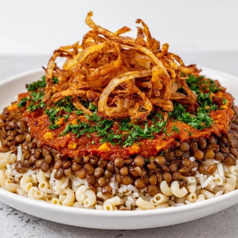 A hearty bowl of Egyptian Koshari, layered with rice, lentils, pasta, and vibrant tomato sauce.