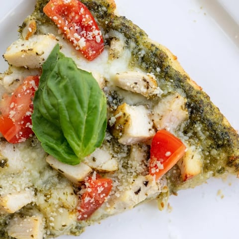 Freshly baked Chicken Pesto Pizza with melted mozzarella, tender chicken, and juicy tomato slices on a thin, golden crust.