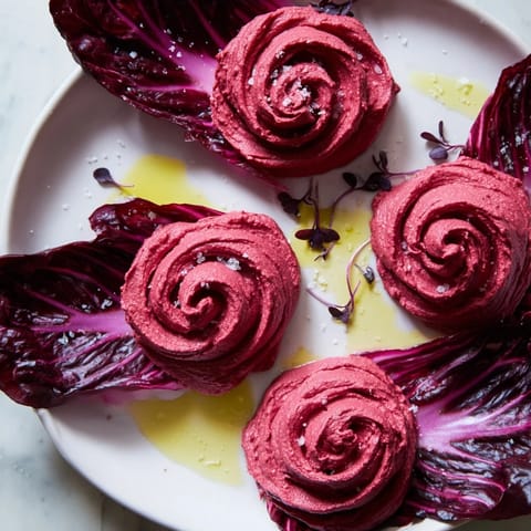 A close-up of The Velvet Rose appetizer: richly colored beet hummus swirled like a dark red rose.