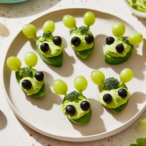 Attaque d'Extraterrestres Snacks Verts arranged with vibrant guacamole and olive eyes on a platter.
