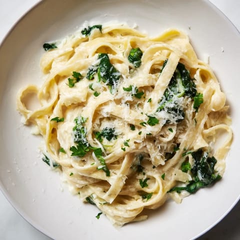 This beautiful photo shows a bowl of creamy Spinach Fettuccine Alfredo, ready to serve with extra Parmesan cheese.