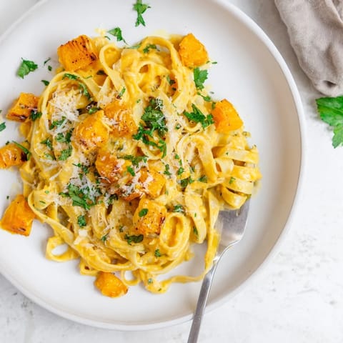 Golden roasted butternut squash pasta with creamy sauce, served steaming in a rustic bowl.