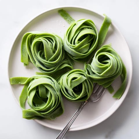 Homemade spinach pasta dough resting on a floured surface, showcasing its smooth texture and emerald hue from fresh spinach puree.
