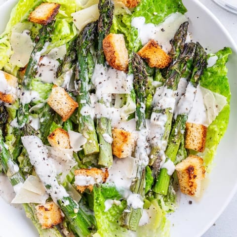 Freshly prepared Roasted Asparagus Caesar Salad featuring tender asparagus, creamy yogurt dressing, and shaved Parmesan.