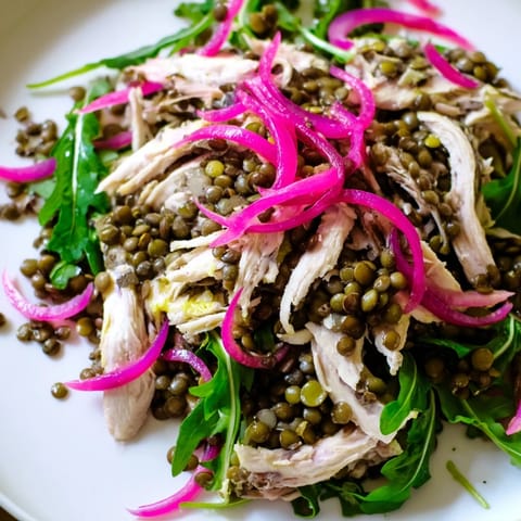 Lentil & Chicken Spring Salad served in a rustic bowl, featuring vibrant greens, halved cherry tomatoes, and a light mustard vinaigrette glistening.  