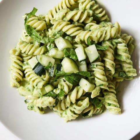 Tossing the creamy Green Goddess Pasta Salad in a large bowl showcases crisp cucumber and vibrant herbs.