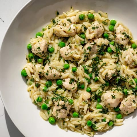 A close-up of Lemon Herb Chicken Orzo Skillet garnished with fresh parsley and dill, steam rising from the one-pan meal.
