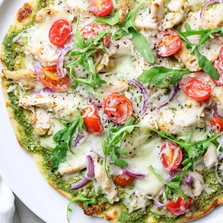 Golden-crusted Pesto Chicken Flatbread slices showcasing tender chicken and fresh arugula.