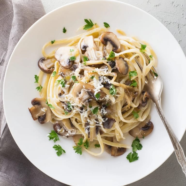 Serving suggestion: Creamy Mushroom Linguine plated with extra shaved Parmesan and a glass of Pinot Grigio beside it.