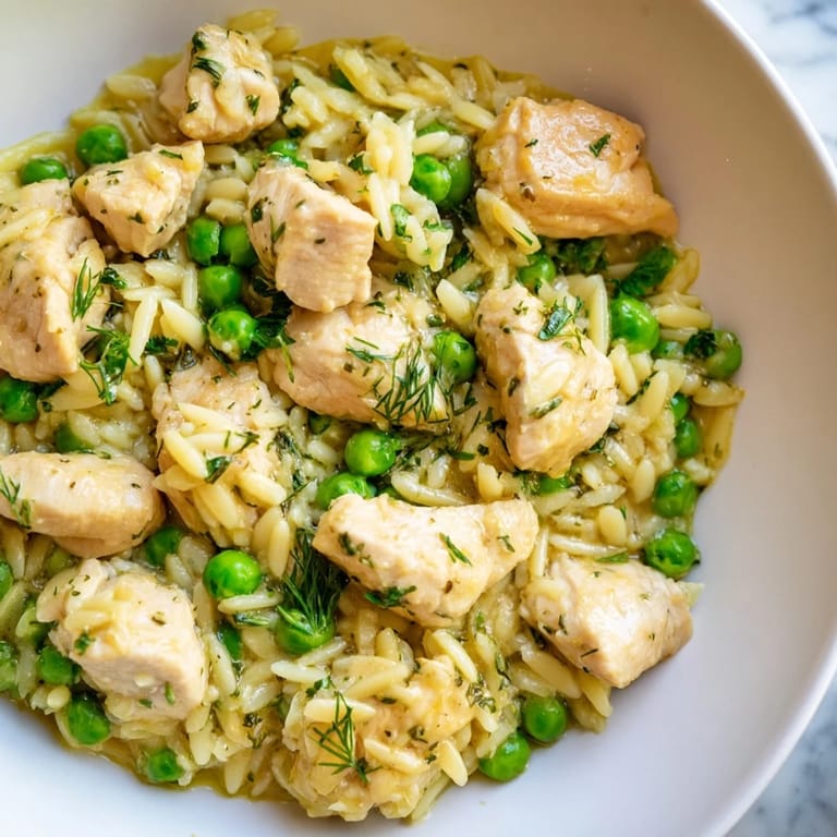 A skillet of Lemon Herb Chicken Orzo with sautéed onions, garlic, and bright herbs, ready for a light spring dinner.