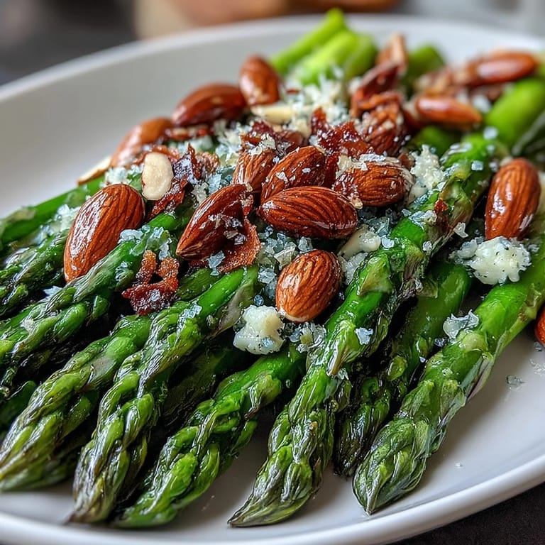 Tender asparagus spears glistening with lemon butter sauce, garnished with crunchy toasted almonds for an elegant vegetarian side.