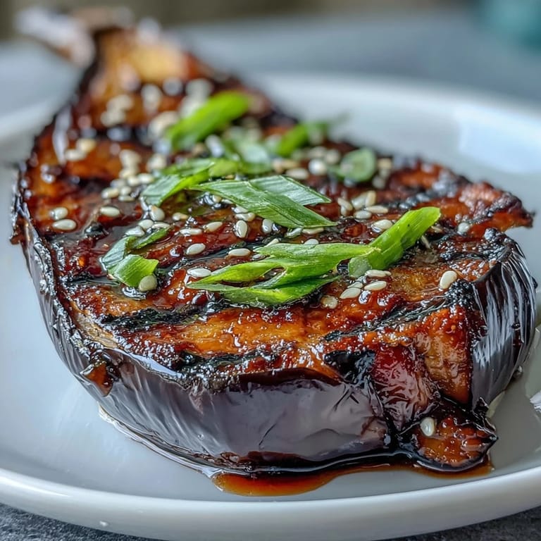 Golden-brown roasted eggplant halves with a glossy miso glaze, served warm and garnished with sliced green onions for a vibrant vegetarian dish.
