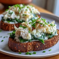 Golden-toasted rye bread generously topped with flaky smoked haddock, wilted spinach, and a dollop of creamy crème fraîche for a savory breakfast.