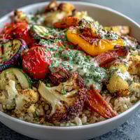 Flavorful Rainbow Roasted Vegetable Bowl with roasted bell peppers, broccoli, and purple cauliflower on fluffy brown rice, drizzled with herb sauce.