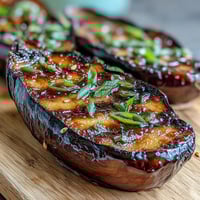 A close-up of miso glazed eggplant, tender roasted halves caramelized with a rich, savory-sweet miso topping, garnished with sesame seeds.