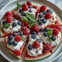 Festive 4th of July Watermelon Pizza topped with fresh berries and whipped cream clouds.
